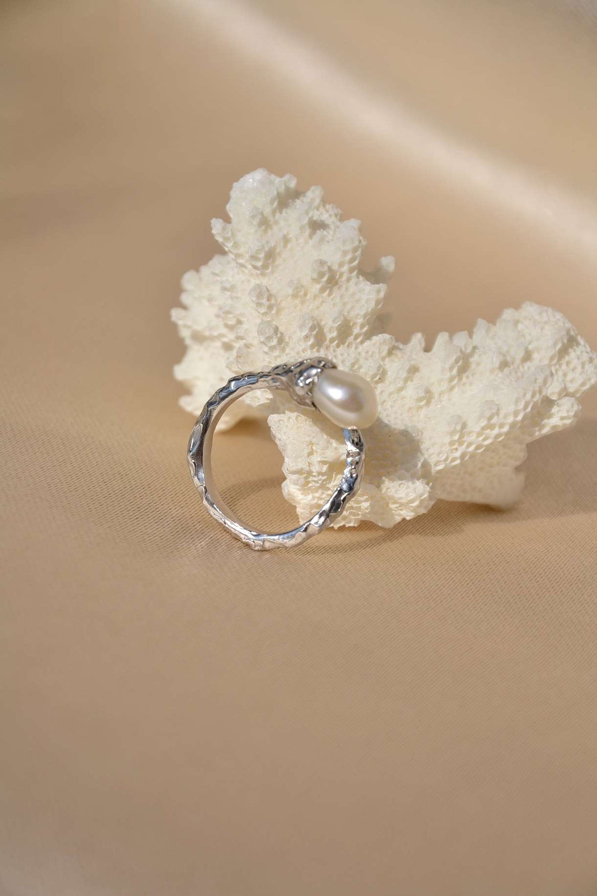 Side view of the Veil ring showing the curved silver setting around the natural baroque pearl