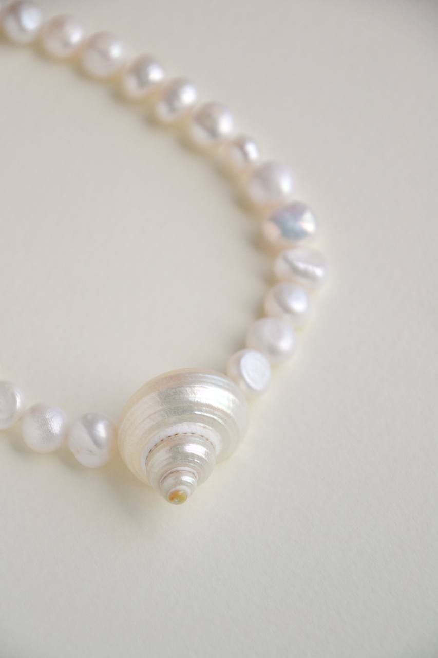 Close-up of the SirenCore choker showing natural pearls and its ocean shell accent