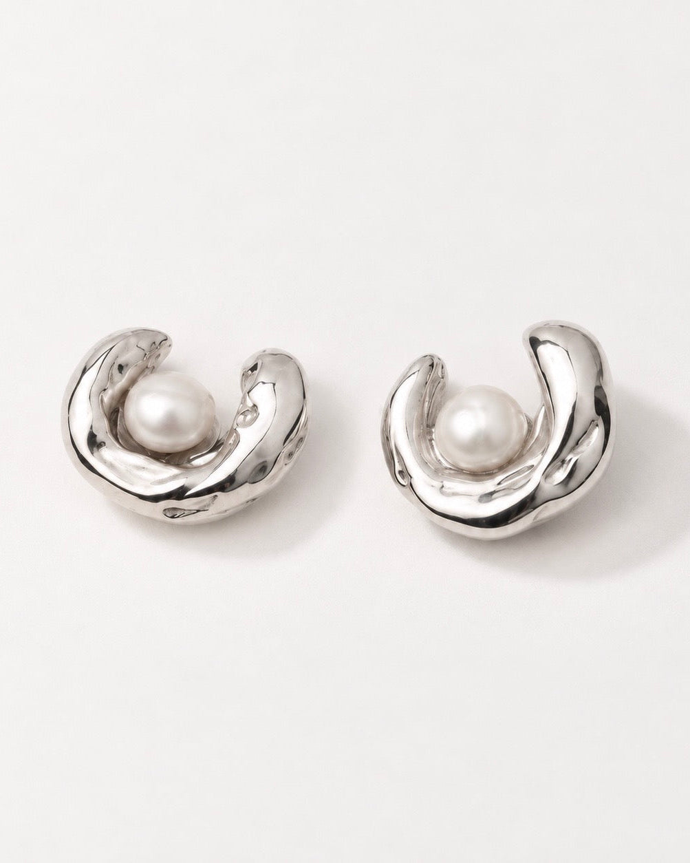 sculptural silver pearl stud earrings on model ear close up