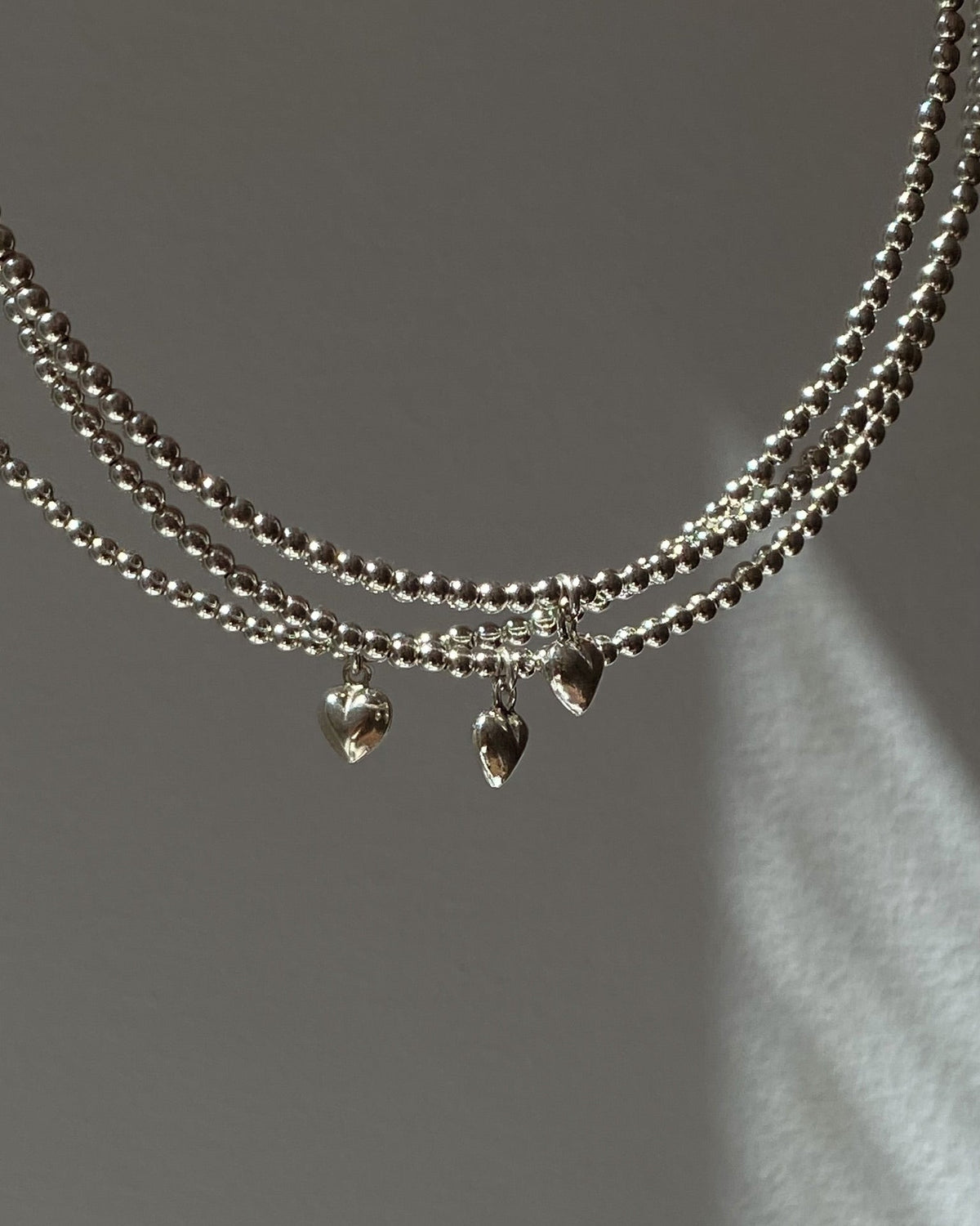 Close-up of the miniature silver heart pendant on the AIRY bead choker