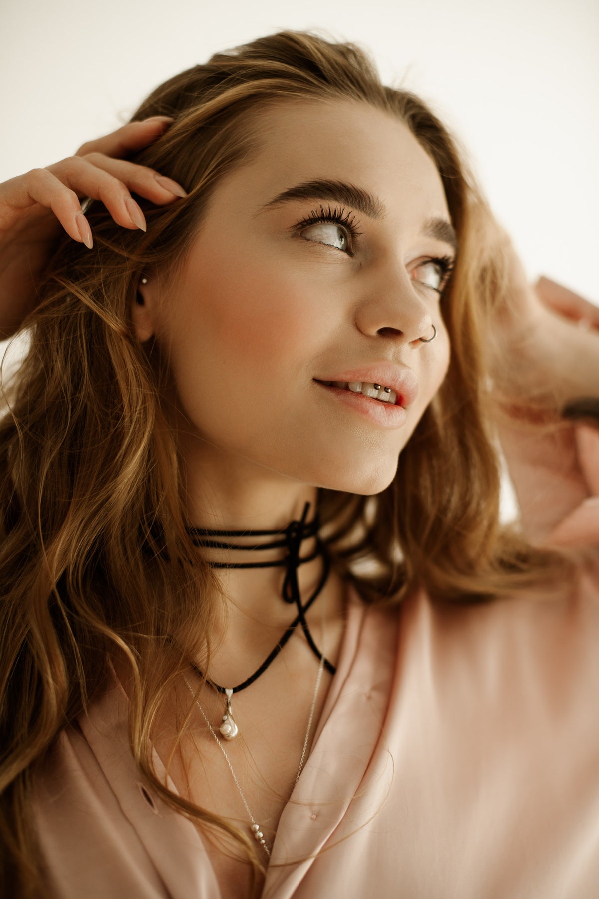 A woman wearing the Tear Drop silver pendant with natural pearl accents on a long black velvet cord