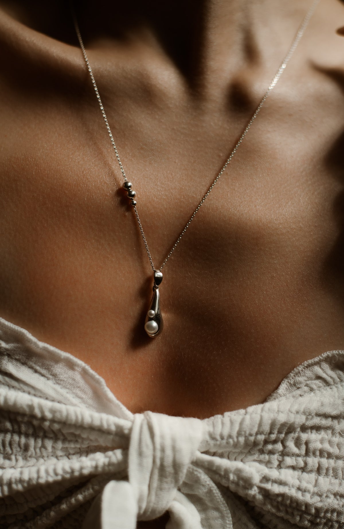 Close-up of the Tear Drop pendant showing its natural pearl inlay and polished silver form