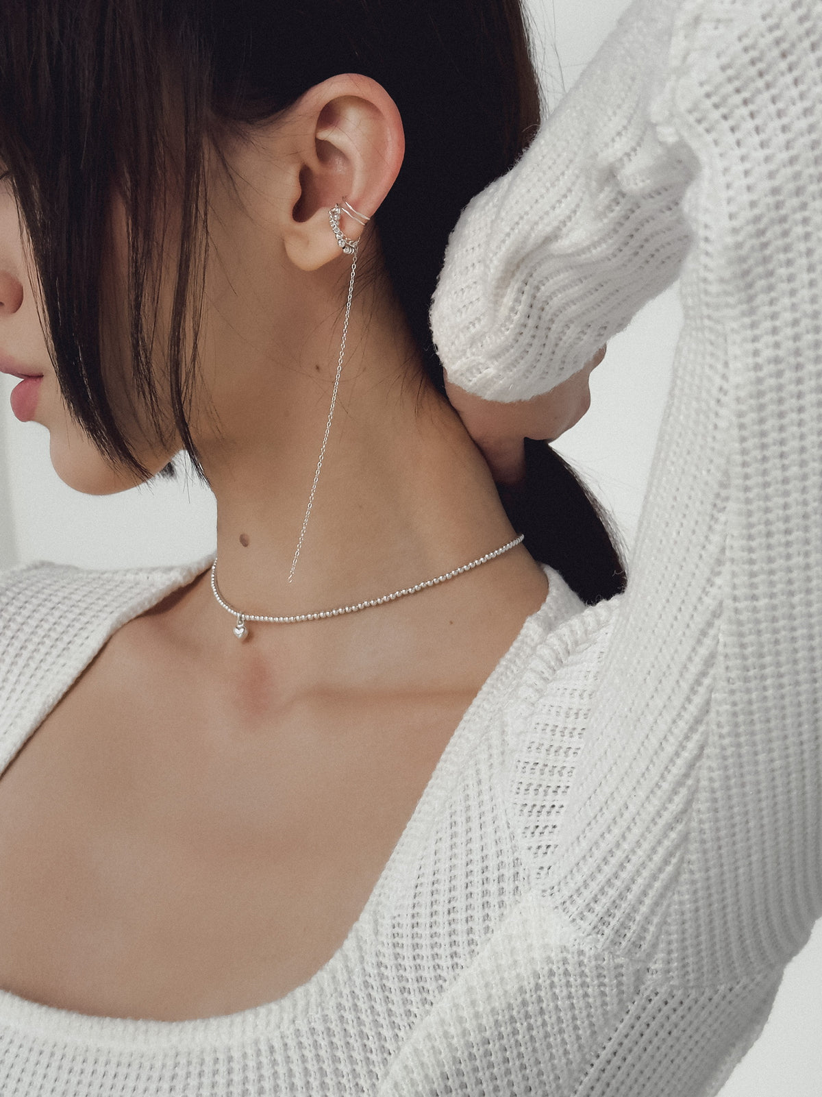 Miley sterling silver chain ear cuff with delicate silver spheres and a long dangling chain, styled on a model’s ear.