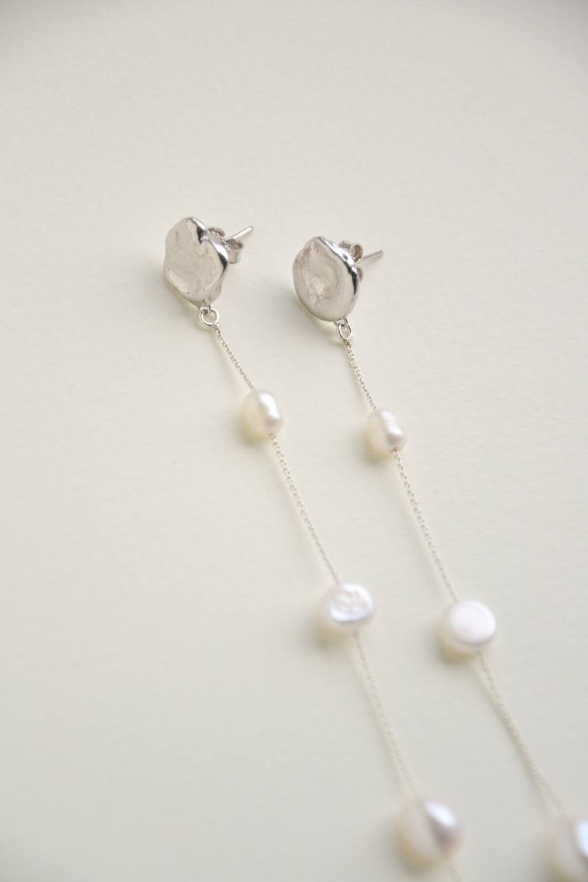 Close-up of the Fonte earrings showing irregular water-cast silver studs and natural pearls