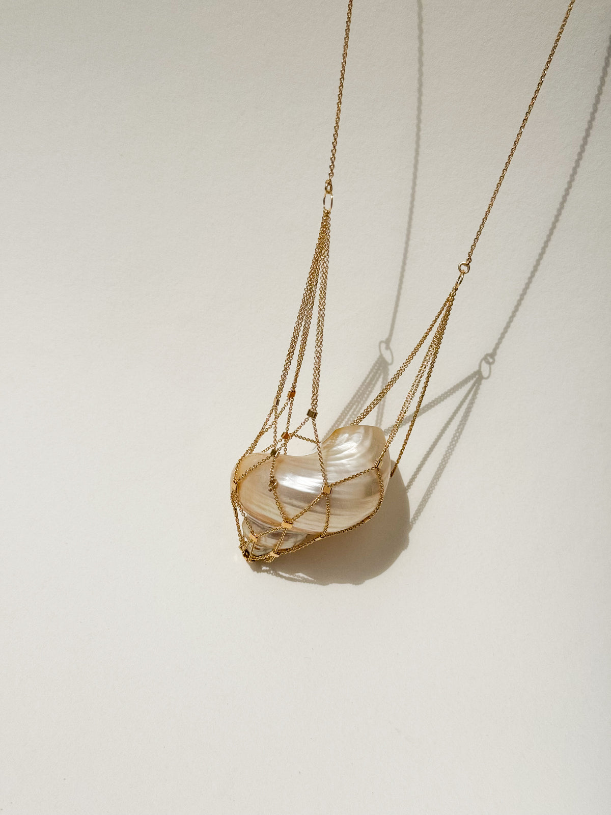 SirenCore shell pendant necklace with a gold-plated sterling silver chain net surrounding an ocean shell