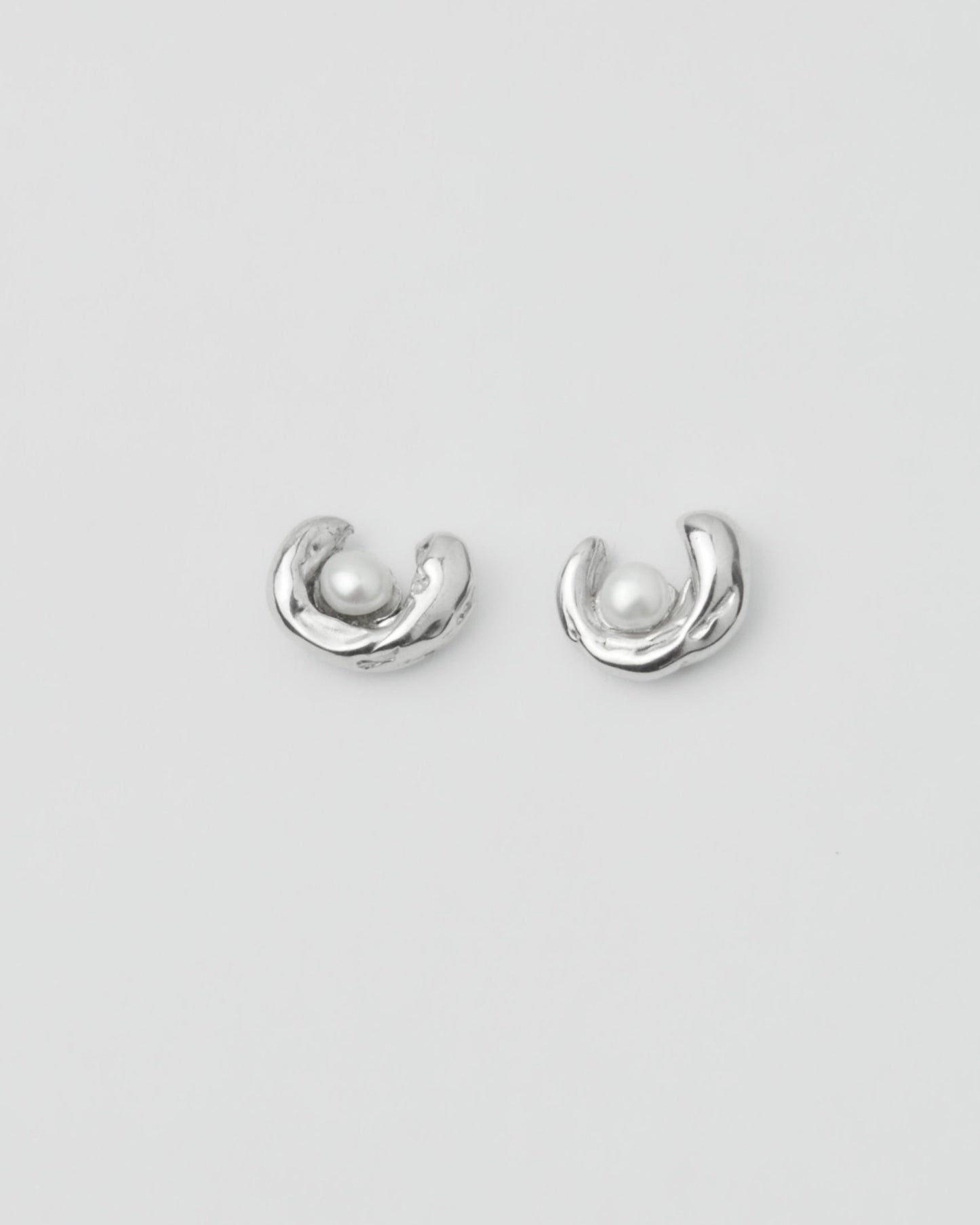 sculptural silver pearl stud earrings on model ear close up