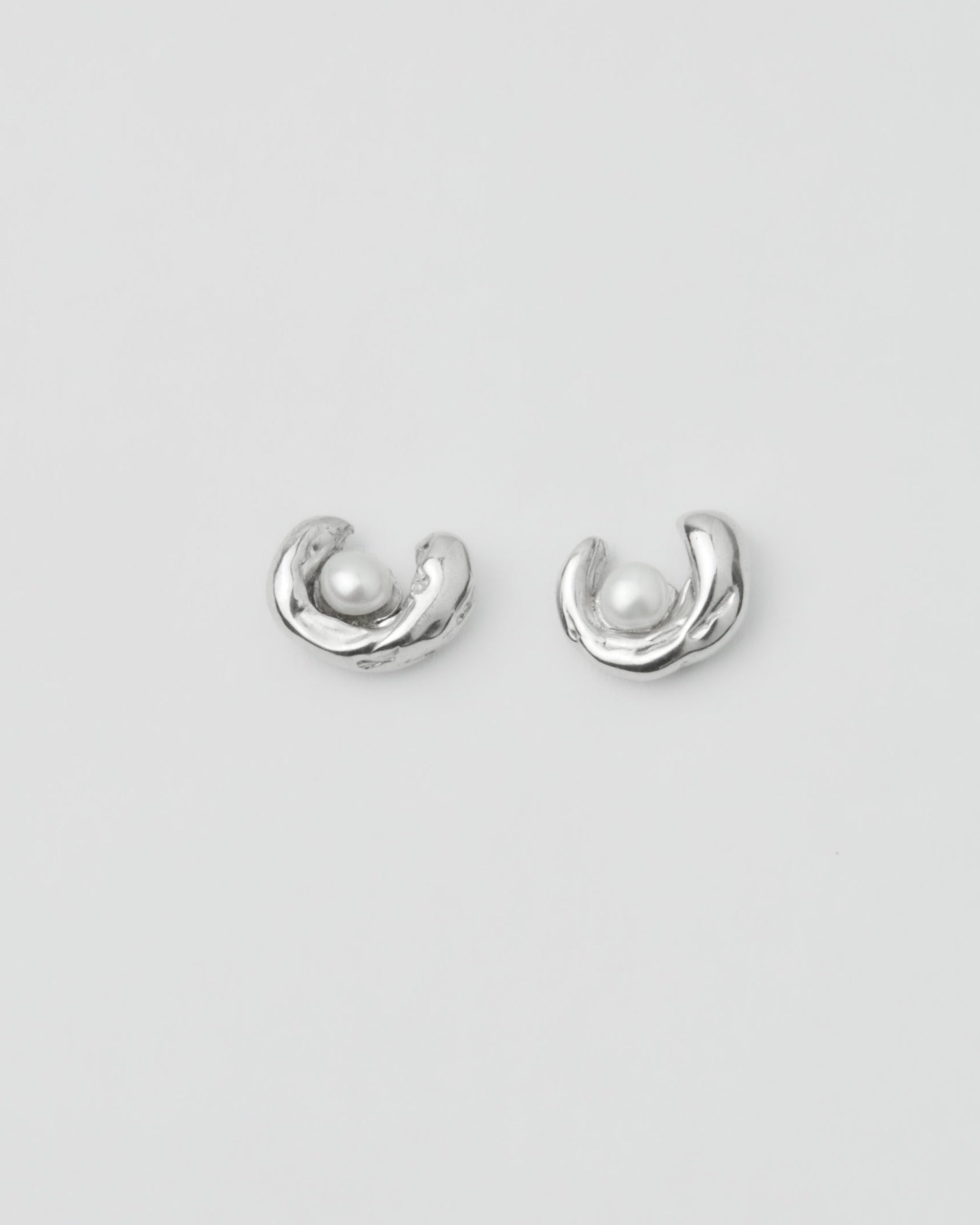 sculptural silver pearl stud earrings on model ear close up