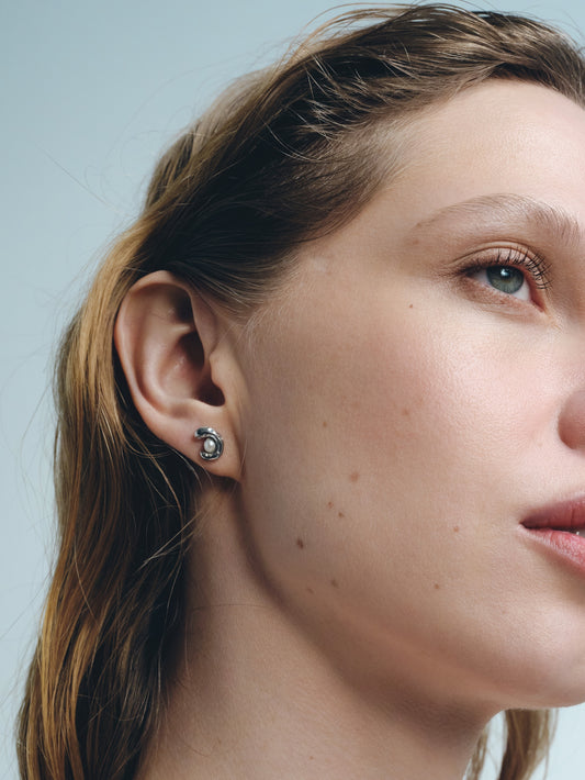small silver stud earrings with pearl worn on ear minimalist jewelry