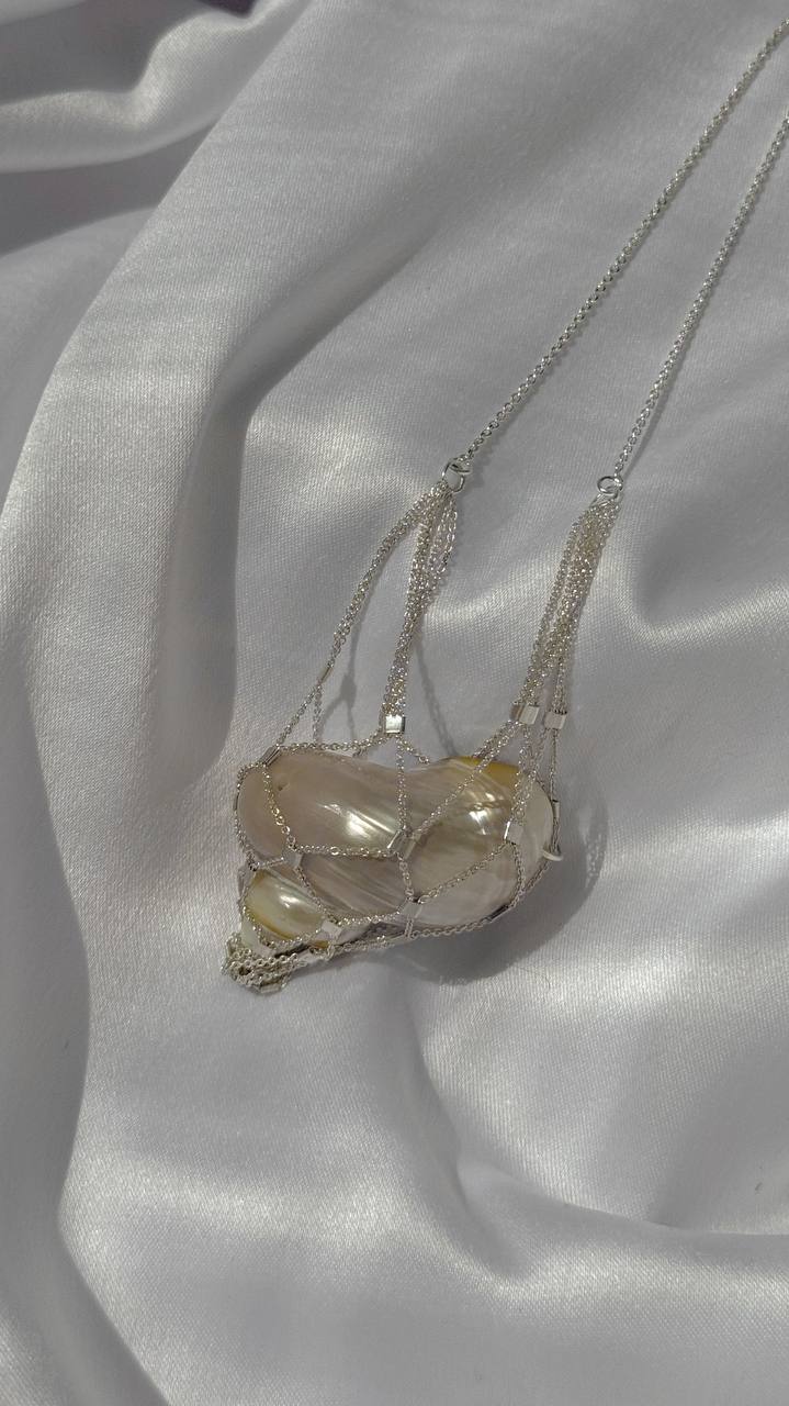 Close-up of the rhodium-plated silver chains wrapped around the shell pendant on the SirenCore necklace
