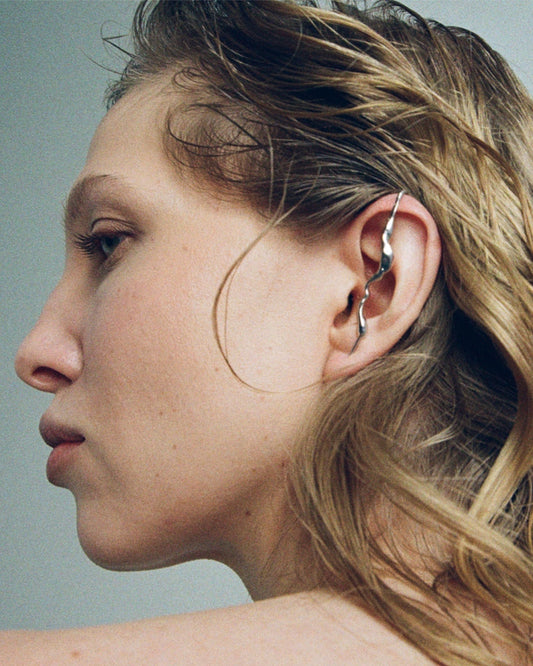 Fluid silver ear cuff worn on ear, sculptural mono earring with organic flowing shape, contemporary jewelry